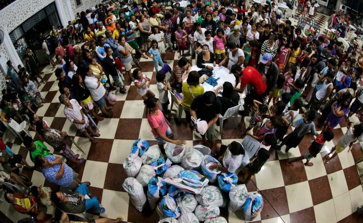 People gather at a gymnasium turned into an evacuation centre for the distribution of relief goods in San Jose city, Nueva Ecija province.
