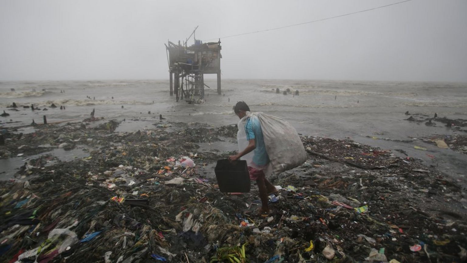 A Filipino man scavenges recyclable materials by the sea as strong winds and rains caused by the typhoon hit the coastal town of Navotas, north of Manila