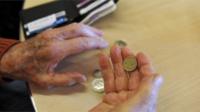 Elderly person holding £1 coin