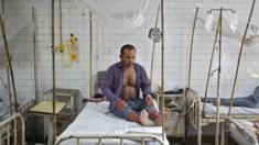 A patient awaits routine check-up as he sits under a mosquito net inside a dengue ward of a government hospital in New Delhi, India,