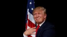 US presidential candidate Donald Trump hugs a US flag