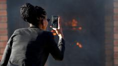 A women uses a mobile phone to take pictures of a burning school in Mashau Dolly village, Limpopo province, South Africa - Thursday 5 May 2016