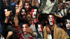young men with their faces painted black, white and red (the Yemeni flag colours) shout and raise their fists