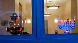 Window in New York showing Christmas tree and menorah