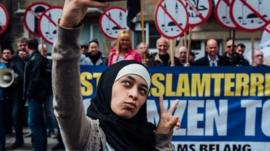 Photo of Zakia Belkhiri taking a selfie with Vlaams Belang protesters in the background