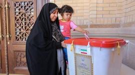 An Iranian woman holds a girl as she casts her vote during a second round of parliamentary elections, in Shiraz (30 April 2016)