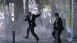 People dodge falling debris as they evacuate an office building