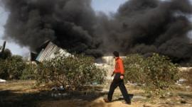 A man walks past a fire after an Israeli airstrike on a wood factory north Gaza