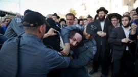 Israeli police officers arrest an ultra-Orthodox protestor objecting to the religious group