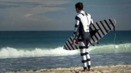 A surfer wearing a black and white striped wetsuit