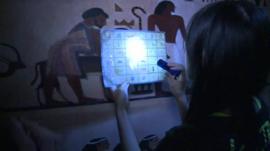 Woman with torch reading hieroglyphics