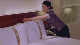 Hotel worker turning down bed