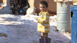 A Syrian child stands in the snow in a refugee camp in the Lebanese Bekaa valley