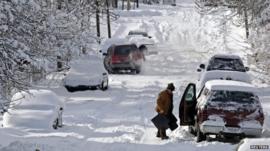 A man clears snow from his car in Indianapolis, Indiana January 6, 2014