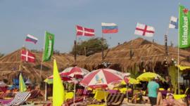Tourists on an Indian beach with international flags