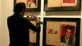 A young man takes a photograph of an artwork at the fair