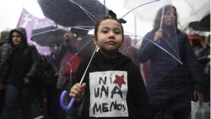 Niña con paraguas con chaleco "ni una menos"