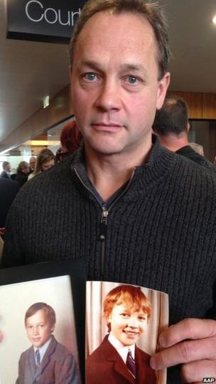 Peter Blenkiron holding photos of himself as a child