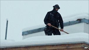 A security officer shovels snow off of a rooftop at the world economic forum in Davos, 26 January