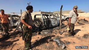 Anti-Gaddafi fighters stand in front of damaged cars, October 21, 2011, after an attack by Nato on a convoy of Gaddafi loyalists in Sirte