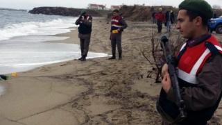 Paramilitary police officers investigate around the body of a migrant on the beach in Dikili, 5 January