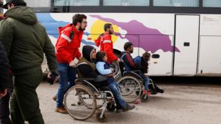 Members of the Syrian Arab Red Crescent assist the families of opposition fighters, board a bus during a government-led evacuation from the rebel-held al-Waer neighborhood, in the western outskirts of the central city of Homs, Syria, 18 March 2017