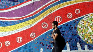 An Iranian man walks past a mural on a street in the capital Tehran