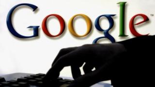Woman at keyboard with Google logo behind