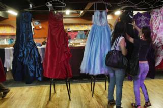 Women look at prom dresses at Project Prom, an event offering free dresses, handbags, shoes and accessories to high school students on May 22, 2009 in New York City