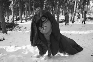 A soldier walks with a parachute to the thermal shelter he is building