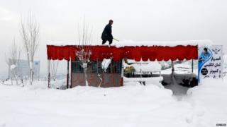 An Afghan man removes snow from his shop on the outskirts of Kabul