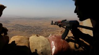Iraqi Kurdish Peshmerga fighters overlooking a town from the top of Mount Zardak, about 25km east of Mosul