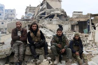 Rebel fighters sit on rubble as they wait to be evacuated from eastern Aleppo, Syria December 16, 2016