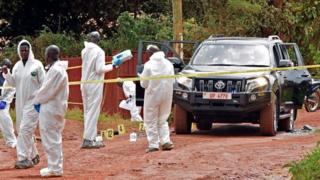 Ugandan police in white protective suits at a murder scene