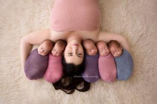 Kim Tucci lies on a rug with her quintuplets