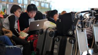 Passengers use their laptop as they wait for their flight