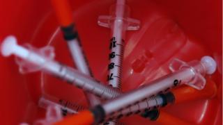 Used syringes sit in a bin after being disposed by heroin addicts