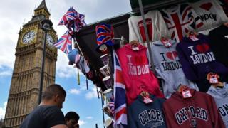 Tourists look at London themed merchandise with Big Ben in background