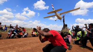 Spectators react as a plane flies over them during the Vintage Air Rally at the Nairobi National Park in Kenya - Sunday 27 November 2016