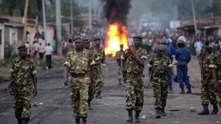 Burundian soldiers walk near a burning barricade erected by protesters - April 2015
