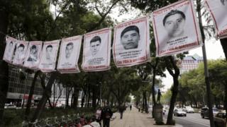 A pedestrian walks past banners with pictures of some of the 43 missing students of Ayotzinapa College Raul Isidro Burgos, along Reforma Avenue in Mexico City, Mexico September 29, 2015.