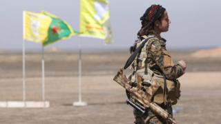 A female Syrian Democratic Forces (SDF) fighter stands with her weapon