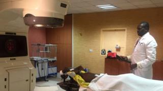 Edger Mulili lies by the radiotherapy machine as doctor looks on
