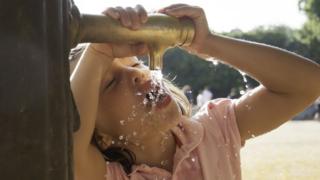 young girl drinking from a tap