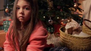 A still from Refuge's new campaign video showing a worried girl next to Christmas presents