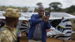 A spectator takes a selfie in front of a non-vintage support aircraft that landed in Nairobi National Park in Kenya, Sunday 27 November 2016