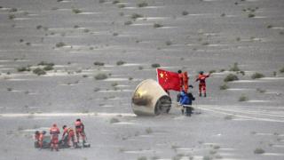 People with a Chinese flag retrieving a module from the desert, 26 June 2016
