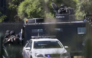 Tactical police officers position themselves outside a factory in an industrial area of Ingleburn, a suburb 40 kilometres (25 miles) southwest of Sydney, Monday, 7 March 2016