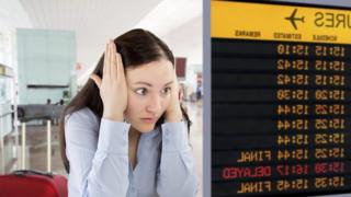 A woman holding her head looking at a board showing a delayed flight