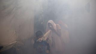 Residents cover their face and run in smoke as a municipal worker fumigates a residential area to prevent mosquitoes from breeding in New Delhi, India, Monday, Sept. 7, 2015